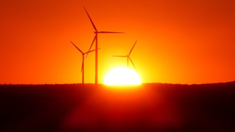 silhouette of wind turbines at sunset